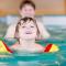 Happy little kid boy and his father swimming in an indoor swimming pool. Active happy kid boy wearing safe swimmies. Family time.