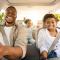 Happy family in a car, looking excited to be going somewhere, lots of trees outside the windows