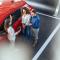 A young professional couple at a dealership being shown a red car by a salesperson