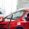Young woman is happy to buy new red modern car at dealership. Business sale showroom of vehicle.