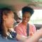 A teenage driver behind the wheel smiling next to her mother in the passenger seat