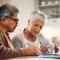 Laptop, finance and senior couple in home for budget, taxes and mortgage payment. Retirement, marriage and man and woman with paperwork for life insurance, investment and bills for online banking