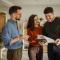 Real estate agent discussing documents agreement terms with happy young couple in modern home