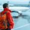 Women with red jacket and backpack waiting at the airport during a rainy day
