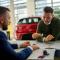 Car salesman and a customer engage in a discussion at a dealership table