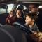 Happy parents and their kids having fun while testing new car in a showroom
