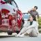 Two people calling for help after a car accident, showing a damaged vehicle