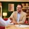 Two professionals seal an agreement with a handshake in a cozy office, with laptop and documents nearby