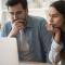 A man and woman look worried at the computer