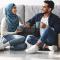 Young homeowners drink coffee together while sitting on the floor of a room surrounded by moving boxes