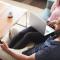 Overhead shot of a couple relaxing at home on their couch. The man is watching tv and the woman is surfing on her laptop.