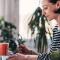 A woman drinking a cup of coffee enters her credit card info online