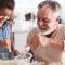 A grandpa bakes with his granddaughter in a bright sunny kitchen