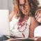 A mom and her son look at something on their laptop while relaxing at home on the couch