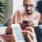 Close up shot of two men on a couch, both of them looking at their mobile devices