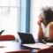 An older professional woman gazes out the window while taking a break from working on her laptop at home