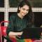 A young professional works on her laptop outside of a student campus