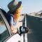 Woman popping head out the passenger window of a white car in a desolate location on the side of the road
