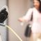 Woman locking electric vehicle as she leaves it to charge