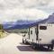 A white truck tows a trailer behind it on a mountain road