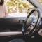 A woman looks in the window of her car to see her keys locked inside