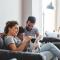 Young family cuddles with their dog on the couch in their new home