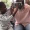 Grandson helps grandpa with virtual reality headset in living room