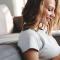 Woman sits on living room floor sending a text to a friend