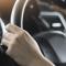 Two hands grip the steering wheel of a car