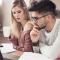 A young couple review their finances with paperwork and a laptop