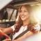 A young woman drives with the sun reflecting behind her