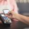 A senior uses their smartphone to pay on the point of sale terminal