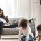 Two parents type away on a laptop while two children colour on the floor