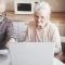 An older couple reviewing paperwork and working on a laptop