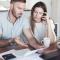 A man looks frustrated as he talks to his partner about the monthly bills