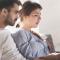 A man and woman review paperwork as they sit on the couch