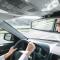 A woman is seen smiling in the rear-view mirror as she drives down a highway