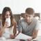 A woman sips her coffee as a man points to a document