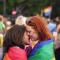 two women embracing at pride in berlin draped in a rainbow flag.jpg