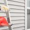 a hardhat and gloves lying on a ladder outside of a house