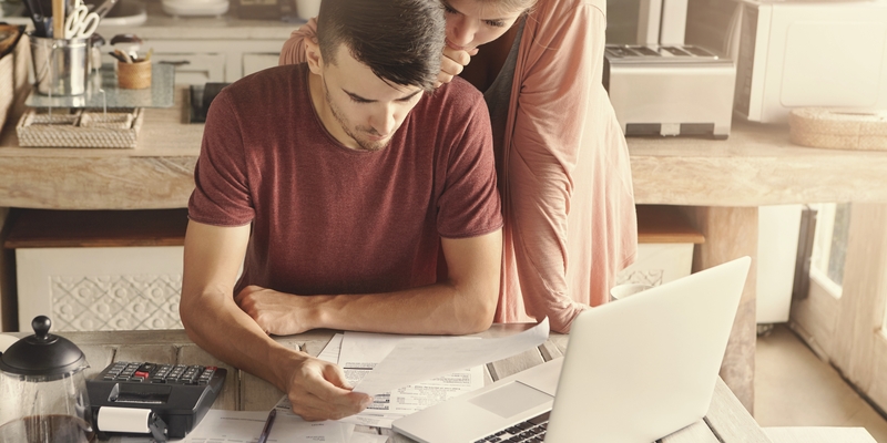 couple leaning over paperwork looking anxious